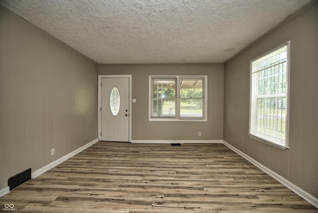 foyer entrance featuring baseboards, a textured ceiling, and wood finished floors