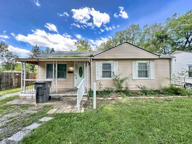 ranch-style home with covered porch, a front yard, and fence