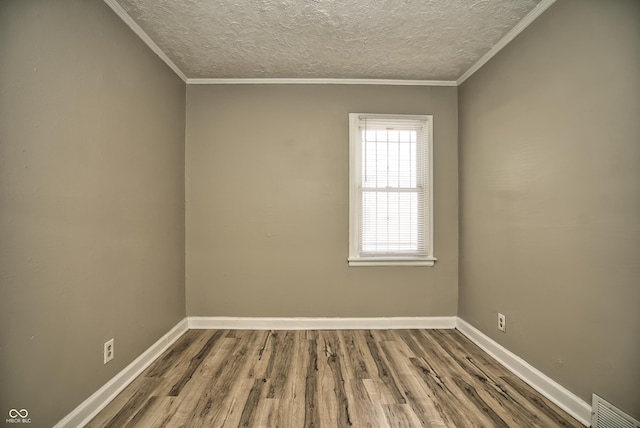 spare room featuring visible vents, baseboards, wood finished floors, and ornamental molding