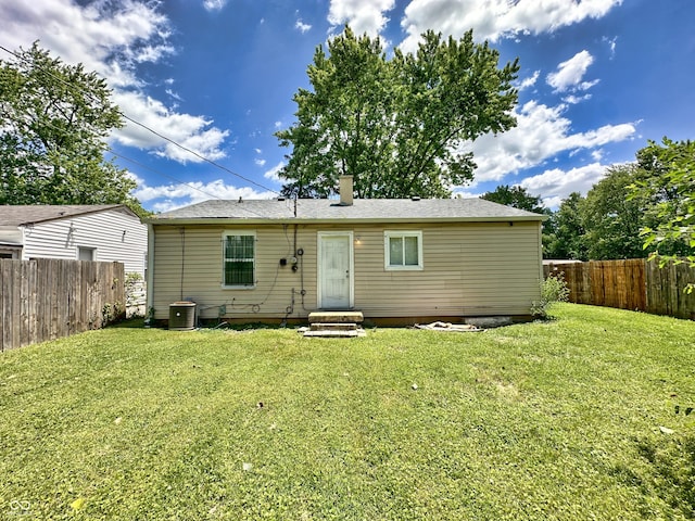 back of property with cooling unit, entry steps, fence private yard, and a yard