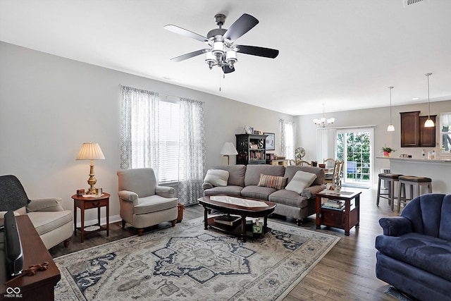 living area featuring ceiling fan with notable chandelier, wood finished floors, and baseboards