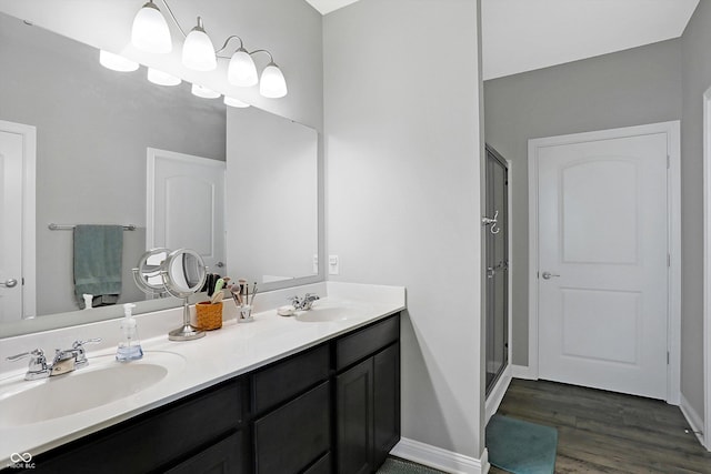 bathroom with wood finished floors, a sink, baseboards, and double vanity