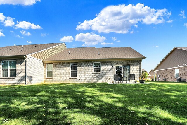 rear view of house featuring a yard, brick siding, a patio, and a shingled roof