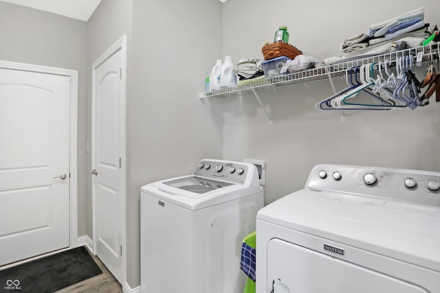 clothes washing area featuring laundry area, independent washer and dryer, and wood finished floors