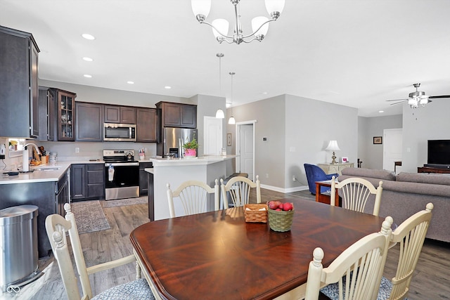 dining room with light wood-type flooring, baseboards, ceiling fan with notable chandelier, and recessed lighting