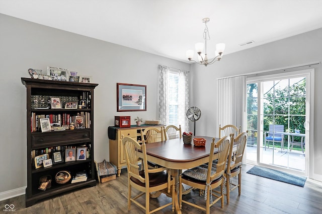 dining area with a chandelier, wood finished floors, visible vents, and baseboards