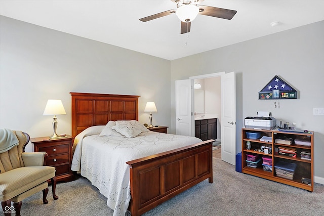 bedroom featuring light carpet, ensuite bath, and a ceiling fan