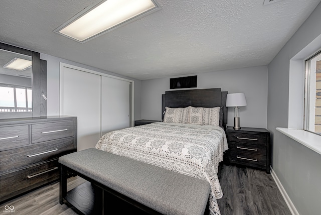 bedroom with a closet, dark hardwood / wood-style flooring, and a textured ceiling