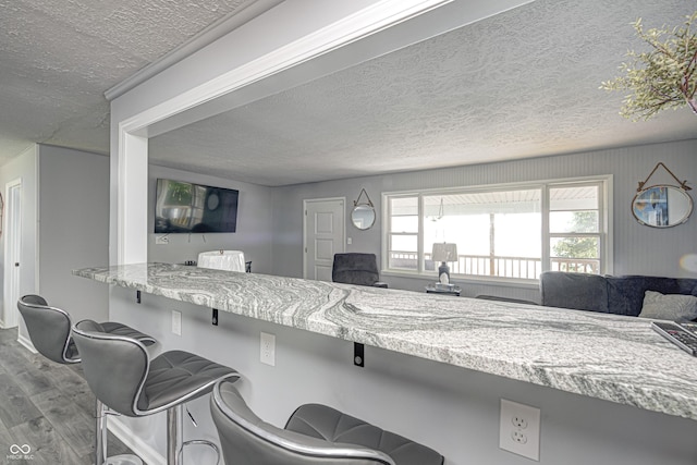 7587 Shady Side Dr, Bloomington, IN 47401 - kitchen featuring a kitchen bar, a textured ceiling, wood finished floors, and open floor plan