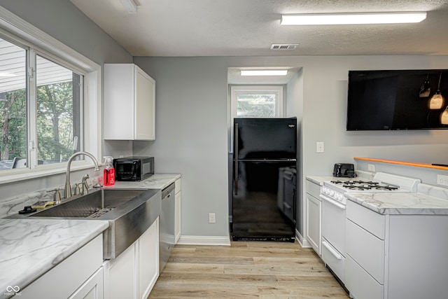 kitchen with black appliances, a healthy amount of sunlight, and light wood-type flooring