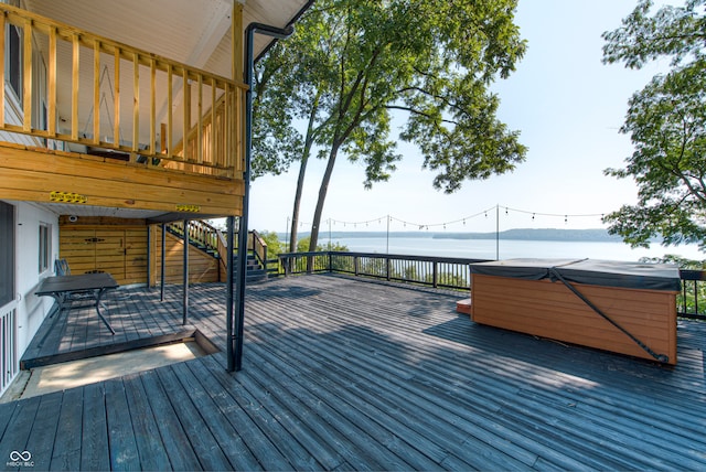 wooden terrace featuring a water view and a hot tub