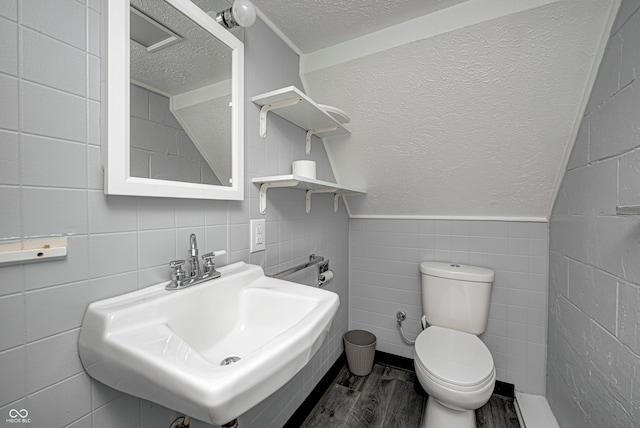 bathroom with toilet, a textured ceiling, sink, decorative backsplash, and tile walls