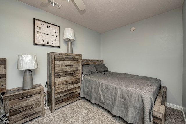 bedroom featuring a textured ceiling, light colored carpet, and ceiling fan