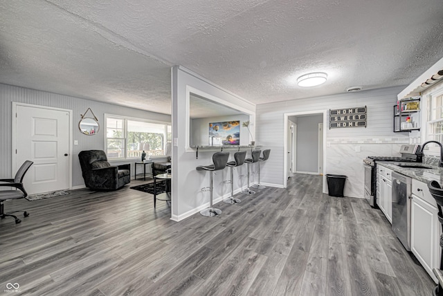 7587 Shady Side Dr, Bloomington, IN 47401 - kitchen with a sink, wood finished floors, a breakfast bar, stainless steel appliances, and white cabinets