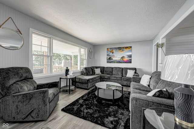 living room featuring a textured ceiling, wood walls, and light hardwood / wood-style floors