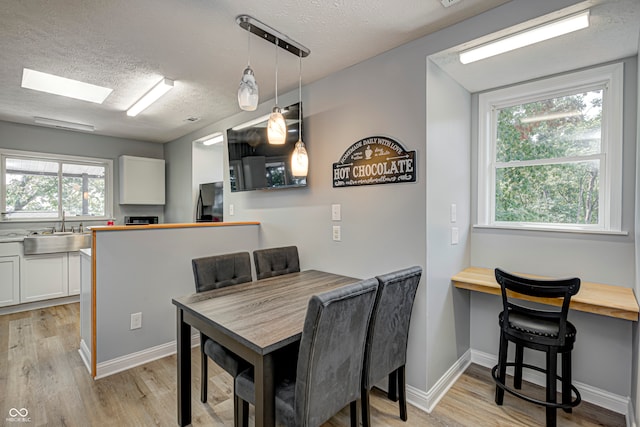 dining room featuring a textured ceiling, light hardwood / wood-style flooring, and sink