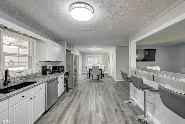 7587 Shady Side Dr, Bloomington, IN 47401 - kitchen featuring white cabinets, light wood finished floors, appliances with stainless steel finishes, a sink, and light stone counters