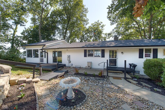 7587 Shady Side Dr, Bloomington, IN 47401 - ranch-style house featuring a chimney, a sunroom, roof with shingles, a deck, and a patio area
