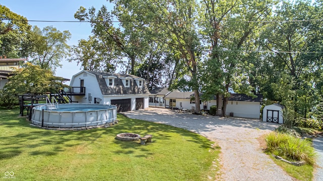 view of front of property featuring a fire pit, a front yard, a storage unit, and a garage