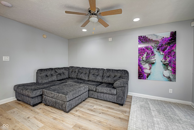 living room with a textured ceiling, ceiling fan, and light hardwood / wood-style floors