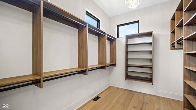 walk in closet featuring a chandelier and light wood-type flooring