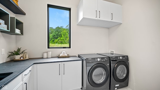 laundry area with washing machine and clothes dryer and cabinets