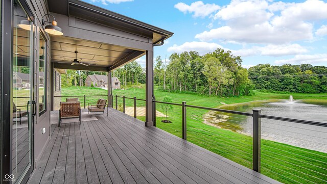 wooden terrace with a water view, ceiling fan, and a yard