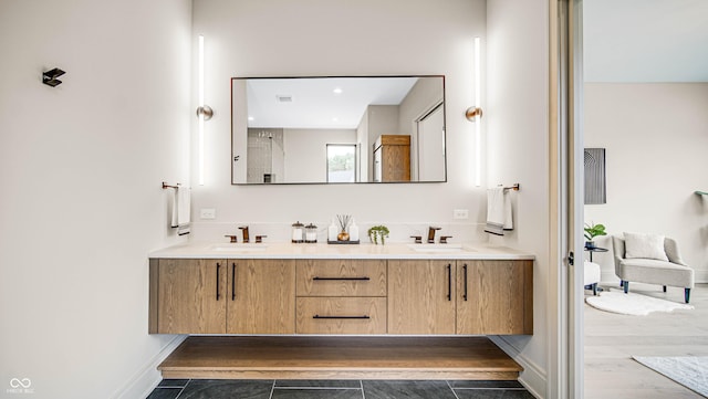 bathroom with double vanity, wood finished floors, a sink, and baseboards