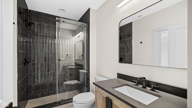 bathroom featuring a shower stall, toilet, and vanity