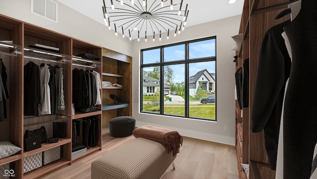 walk in closet with a chandelier and light hardwood / wood-style floors