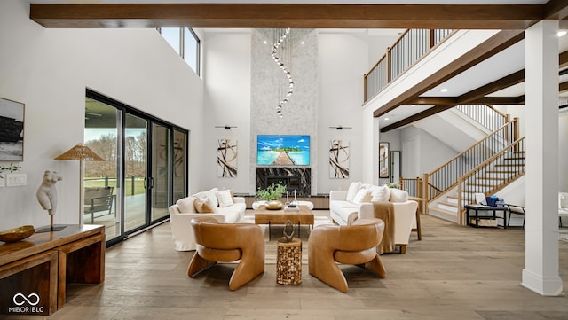 living room with a high ceiling, beamed ceiling, and light hardwood / wood-style flooring