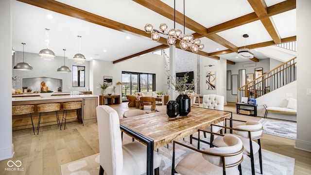 dining area featuring an inviting chandelier, beamed ceiling, a high ceiling, and light wood-type flooring