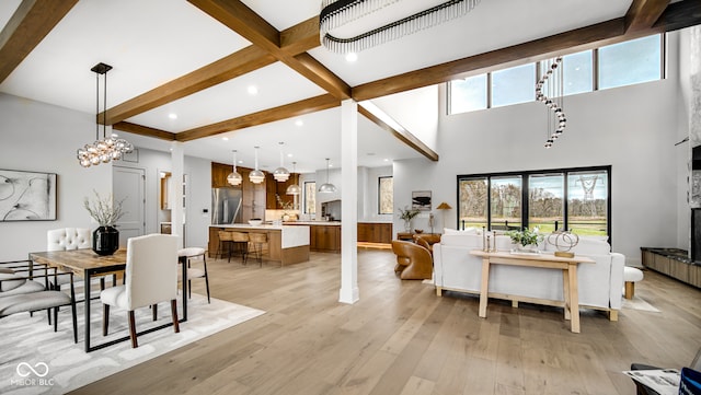 living room with light wood-type flooring, a healthy amount of sunlight, a notable chandelier, and beamed ceiling