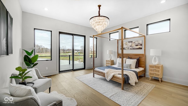 bedroom featuring a chandelier, access to exterior, and light wood-type flooring