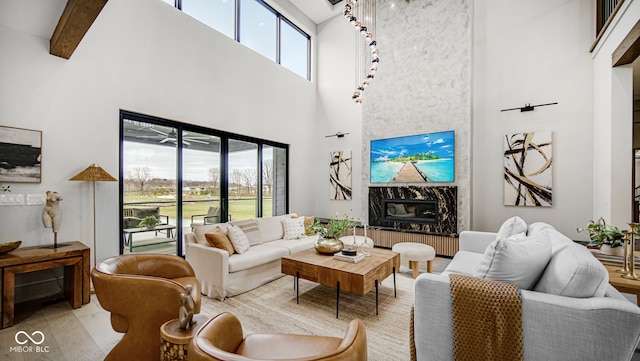 living area featuring a high ceiling, a premium fireplace, and beam ceiling