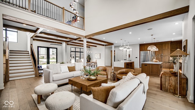 living room with beam ceiling, light hardwood / wood-style floors, and a high ceiling