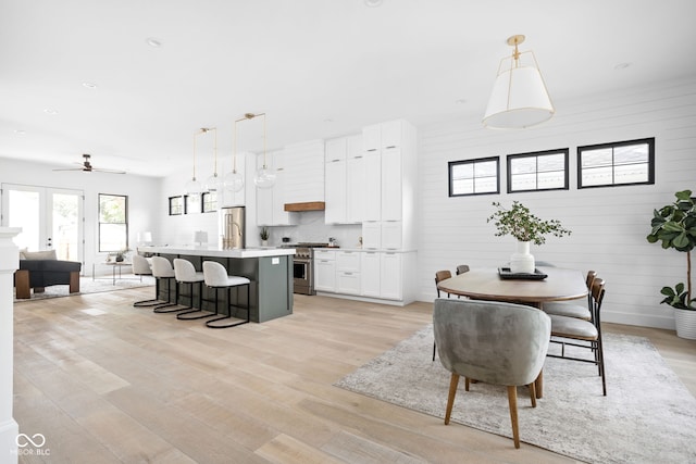 dining area with ceiling fan, wooden walls, and light hardwood / wood-style flooring