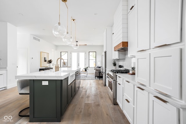 kitchen featuring a kitchen island with sink, stainless steel appliances, sink, hanging light fixtures, and a breakfast bar