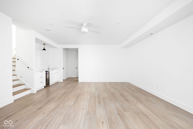 unfurnished room with beverage cooler, ceiling fan, and light hardwood / wood-style floors