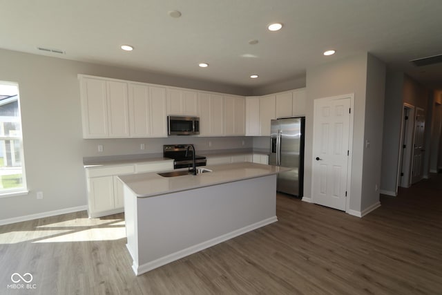 kitchen with sink, light hardwood / wood-style floors, a center island with sink, white cabinets, and appliances with stainless steel finishes