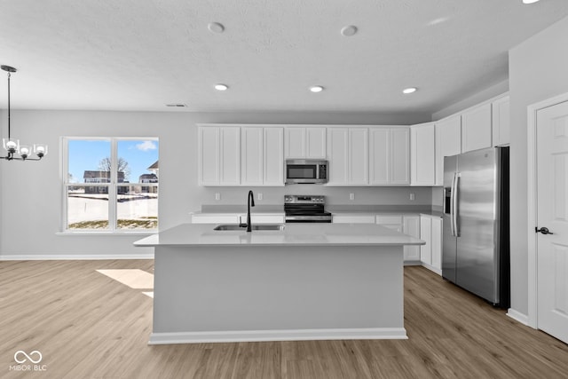 kitchen with sink, white cabinetry, stainless steel appliances, and decorative light fixtures