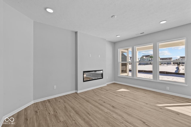 unfurnished living room featuring light wood-type flooring and a textured ceiling