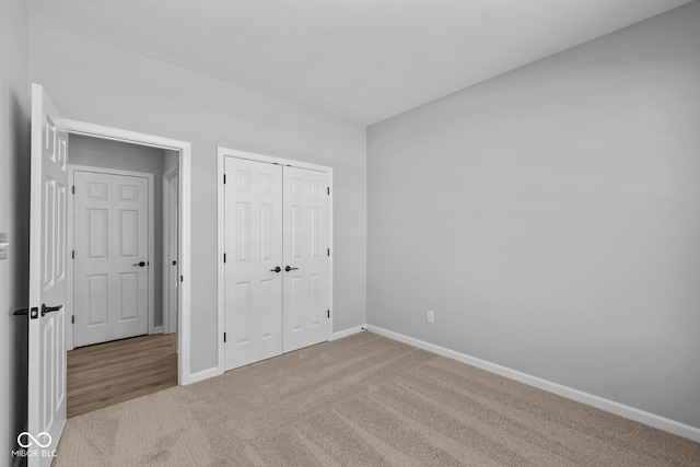 unfurnished bedroom featuring a closet and light colored carpet