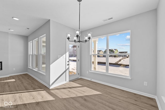 unfurnished dining area featuring a chandelier and wood-type flooring