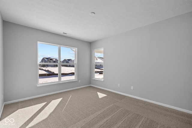 carpeted empty room featuring a textured ceiling