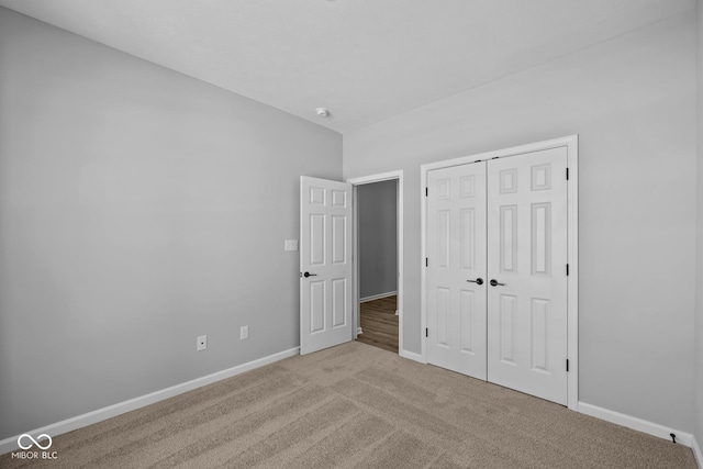 unfurnished bedroom with light carpet and a closet