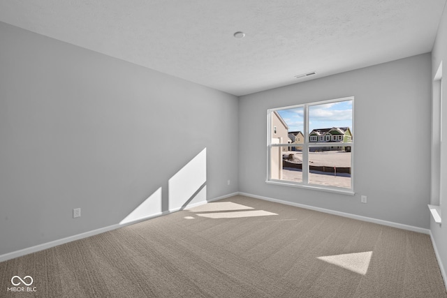 carpeted empty room with a textured ceiling