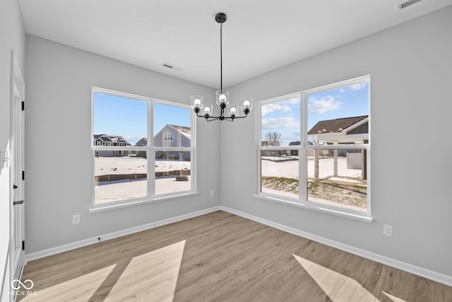 unfurnished dining area featuring a chandelier and light hardwood / wood-style flooring