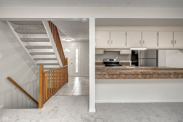 kitchen featuring white cabinets, appliances with stainless steel finishes, light colored carpet, sink, and a textured ceiling