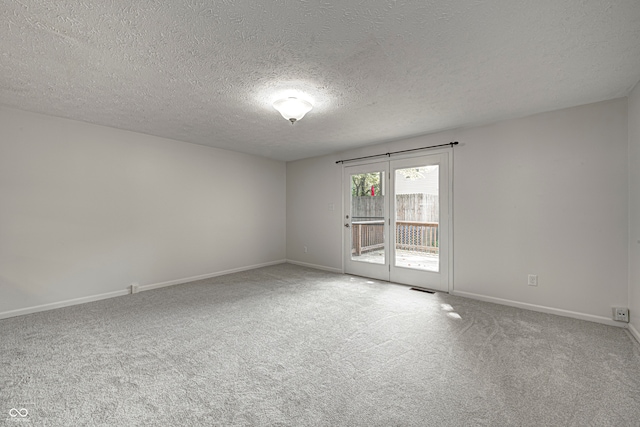 spare room featuring a textured ceiling and light carpet